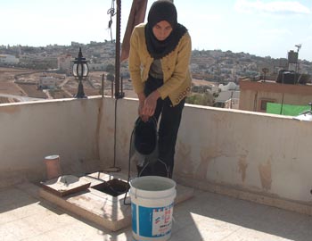 Drawing water from a pit to collect rainwater in a-Dhahiriyah. Photo: Musa Abu Hashhash, B'Tselem., 29 October 2007