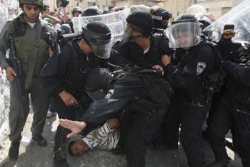 Policemen in uniform drag al-Atrash. Photo: Baz Ratner, Reuters.