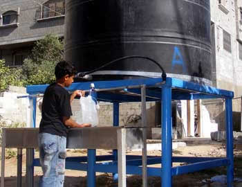 Child filling water from a container provided by OXFAM, at Jabalya refugee camp. Photo: Muhammad Sabah, B’Tselem, 18 Aug. ’10.