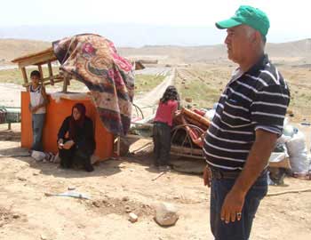‘Alan Dagharmeh and members of his family, residents of al-Farsiya, with the remains of their property. Photo: ‘Atef Abu a-Rub, B'Tselem, 10 August 2010. 