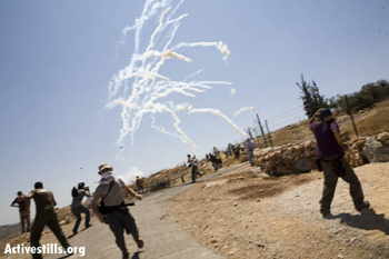 Soldiers shoot tear-gas at demonstrators protesting against the Separation Barrier in Bil'in. Photo: Activestills.org, 24 July '09.