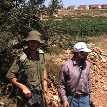 A settler and an army officer in a Palestinian vineyard near Halhul. Photo: Ofir Feuerstein, B'Tselem.