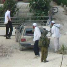 מתנחלים מנפצים שמשת מכונית פלסטינית בנוכחות חייל. צילום: עסירה אל-קיבלייה, 13.9.08.