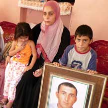 Haifaa a-Tmeizi and her children with a photo of her husband, Yasser a-Tmeizi, whom soldiers killed on 13 Jan. '09 at Tarqumya checkpoint. The case file has awaited a decision by the JAG's Office for over a year. Photo: Musa Abu Hashhash, B'Tselem, 5.9.10