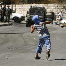 Palestinian boy throws stone towards Israeli border police jeep. Photo: 'Ammar 'Awad, Reuters, 12 Oct. '10