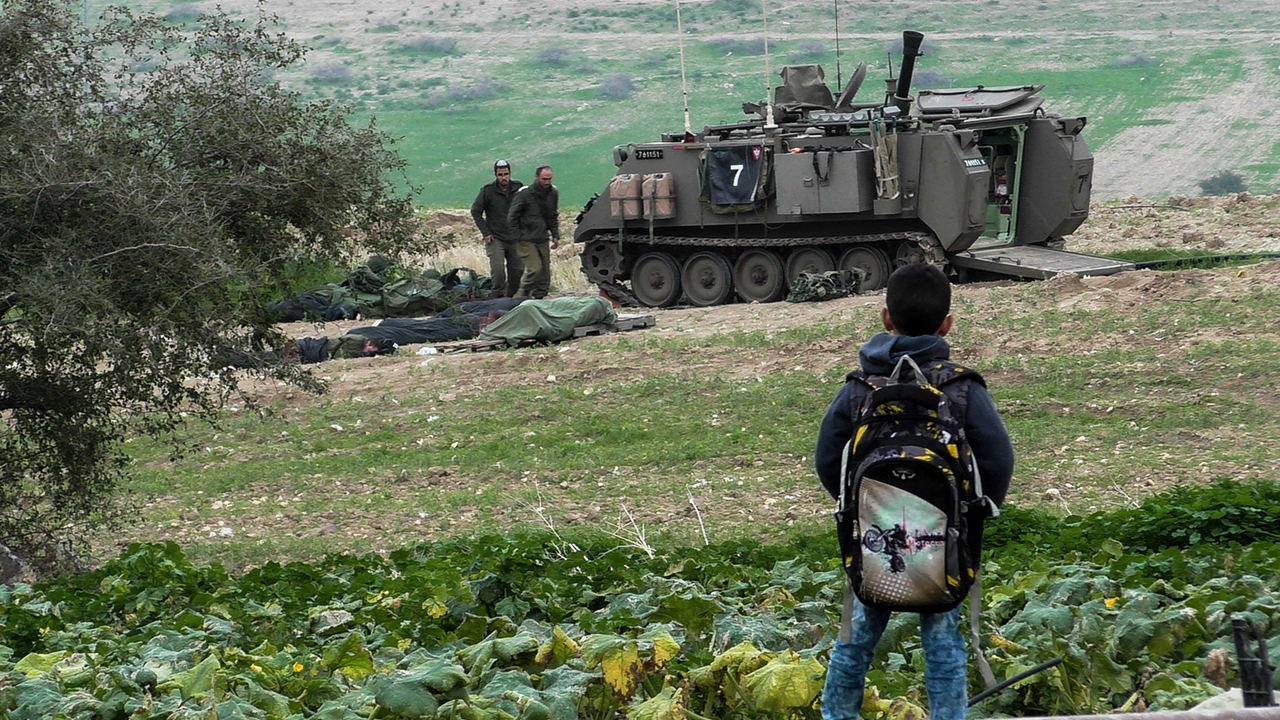 Palestinian boy gazes at armored personnel carrier, al-Farisiyah. Photo by: ‘Aref Daraghmeh, 7 Feb. 2018