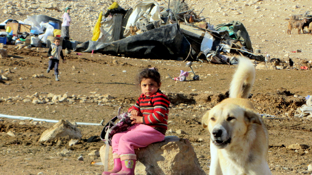 A girl from ‘Ein Karzaliyah against the background of the ruins of the community's buildings, 8.1.14