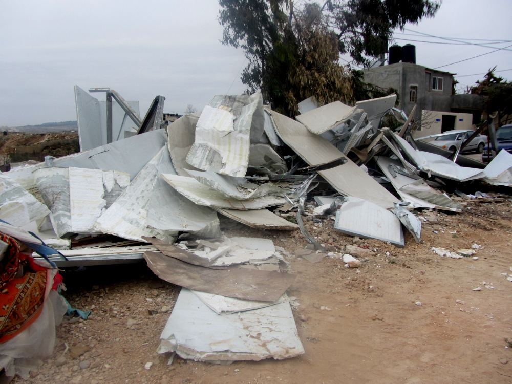 Resti di un edificio prefabbricato utilizzato per negozio di mobili appartenenti alla famiglia Kawassani di Beit Hanina. Nel febbraio 2013, la municipalità di Gerusalemme ha demolito la casa della famiglia in quella posizione, così la famiglia ha vissuto in un prefabbricato hanno eretto lì. In inverno, a causa del clima rigido, i genitori si trasferirono con i loro sette figli minori in un appartamento in affitto e memorizzati alcuni dei loro mobili nel pre-fab. Avevano pianificato di tornare in estate per vivere in essa.