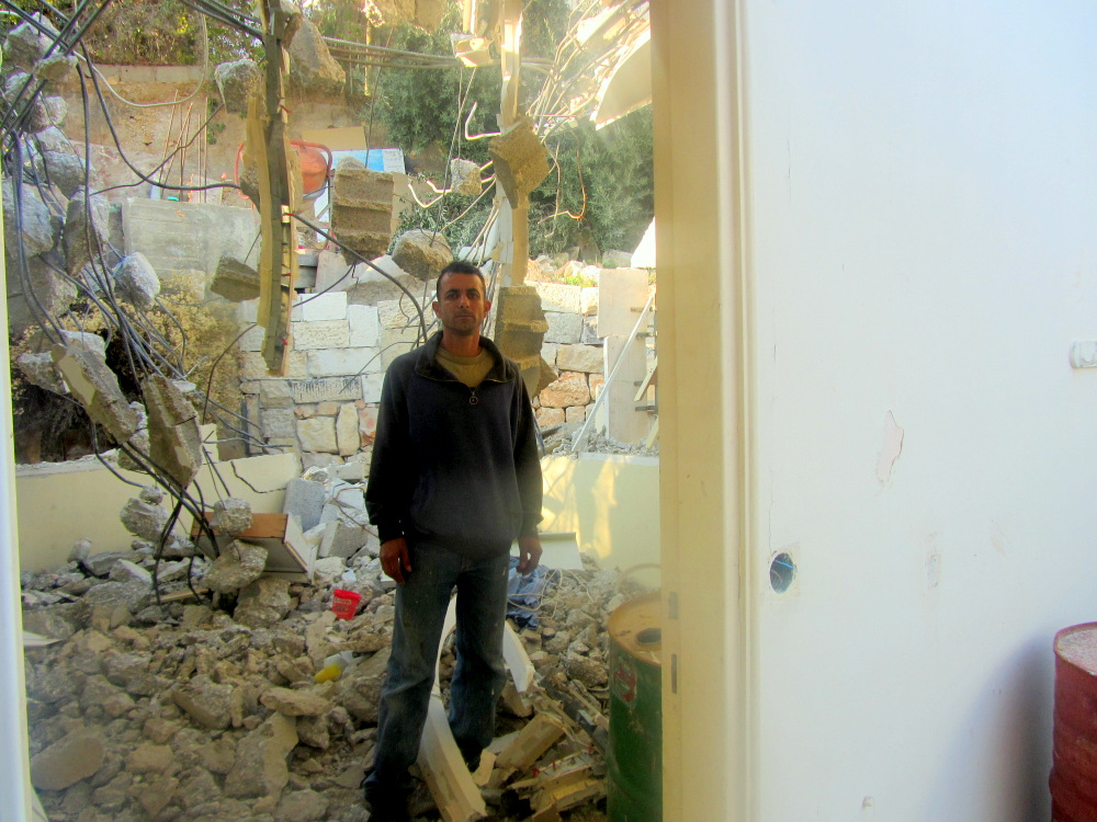 Hamza Abu Tir in rovina della sua casa a Um Tuba, dove aveva vissuto con la moglie ei loro tre figli. Su 14 gennaio, 2014 Abu Tir è stato costretto a demolire la sua casa se stesso dopo aver ricevuto un ordine di demolizione da parte del comune. Intraprendendo la demolizione se stesso, ha evitato di pagare il costo di demolizione da parte del Comune e di altre sanzioni. La famiglia non ha residenza permanente al momento.