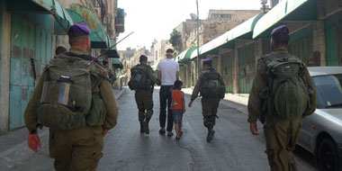 Soldiers taking Karam Maswadeh and his son Wadi' (5 years, 9 months old) through the streets of Hebron, 9 July 2013, Photo: ISM.