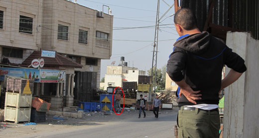 5 November 5 2013, Qabatiya market. The man in the right foreground is standing at the spot where Ahmad Tazaz’ah was hit. Across the road, further in the background, the man in the orange shirt is standing where the soldiers were stationed. Photo by 'Atef Abu a-Rub. 5 November 5 2013, Qabatiya market. The man in the right foreground is standing at the spot where Ahmad Tazaz’ah was hit. Across the road, further in the background, the man in the orange shirt is standing where the soldiers were stationed. Photo by 'Atef Abu a-Rub.