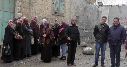 Residents of Bab a-Zawiya neighborhood, Hebron, stand by the closed checkpoint. Photo: ‘Imad Abu Shamsiyeh, B’Tselem, 24 November 2014