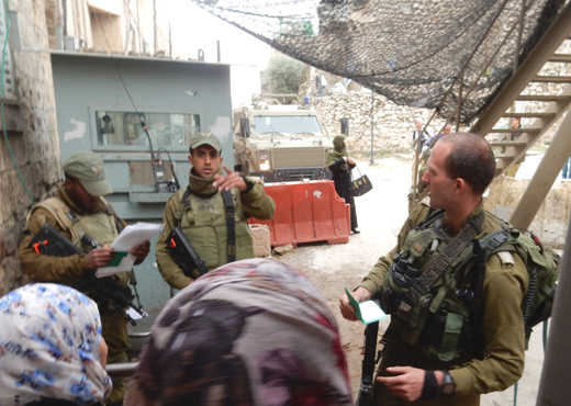 Checking residents’ names at Bab a-Zawiya Checkpoint, Tel Rumeidah. Photo by Musa Abu Hashhash, B’Tselem, 5 Nov. 2015