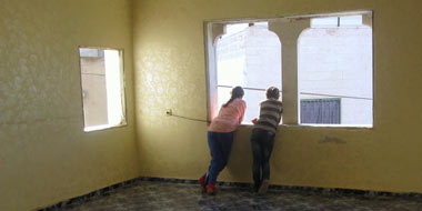 Children look out window of room in their home emptied in preparation for demolition. Photo: Manal al-Ja'abri, B'Tselem.