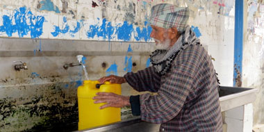 Elderly man fills water container at public multi-faucet sink of Khan Yunis Water Authority&rsquo;s wastewater treatment plant. Photo by Muhammad Sabah, B&rsquo;Tselem, 4 February 2014