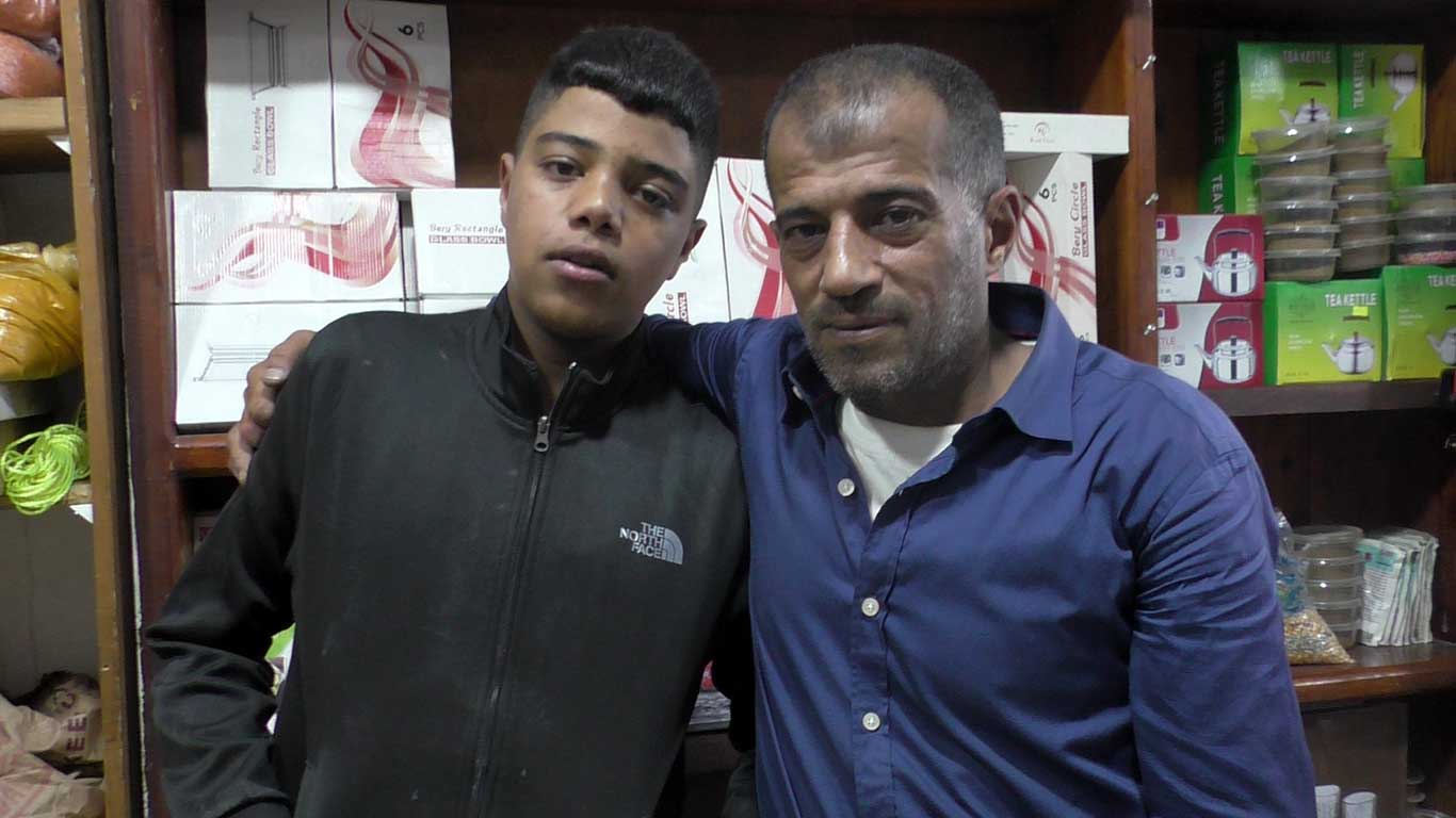 محمد مقبل في دكّان البقالة خاصّته مع ابنه سند. تصوير منال الجعبري، بتسيلم، 22.6.21