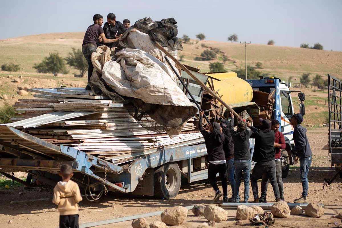 Residents of Ras ‘Ein al-‘Auja loading tent tarpaulins onto a truck before leaving. Photo: Keren Manor, B’Tselem