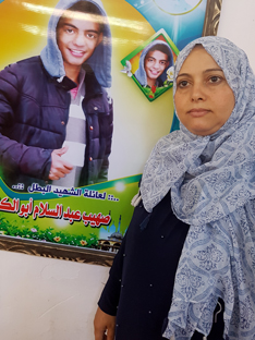 Nisreen Abu Kashef next to a poster in memory of her son. Photo by Olfat al-Kurd, B'Tselem, 10 Oct. 2018