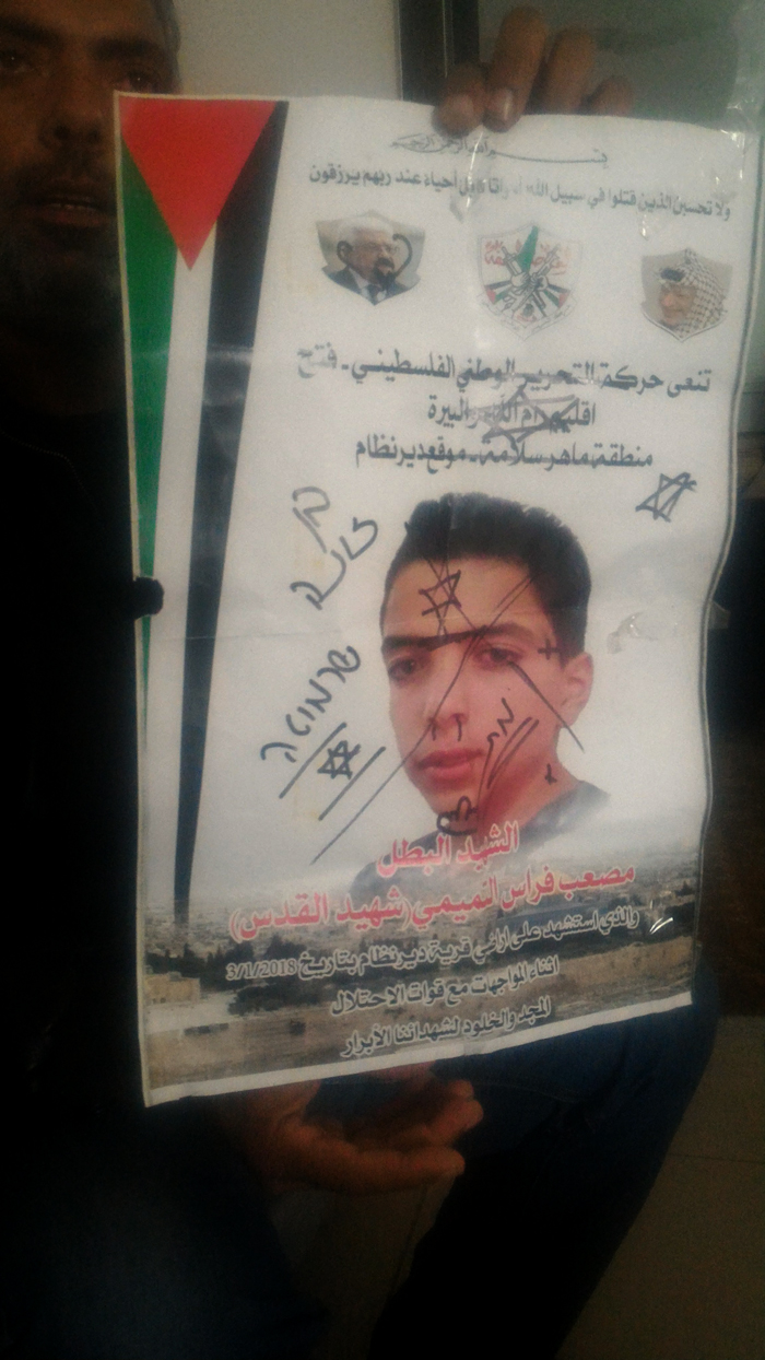 والد مصعب الصوفي يحمل ملصق نعي ولده وقد شوّهه جنود بعد مقتله بيومين