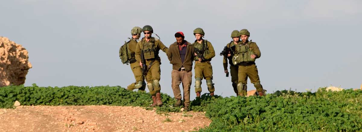 Soldiers detain Ahmad Abu Muhsen after he was assaulted by settlers. Photo by ‘Aref Daraghmeh, B’Tselem, 17 Feb. 2019