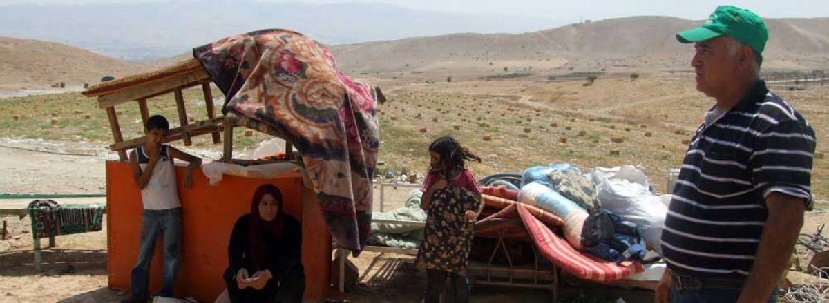 Alan Dagharmeh and members of his family, residents of al-Farsiya, with the remains of their property. Photo: ‘Atef Abu a-Rub, B'Tselem, 10 August 2010. 