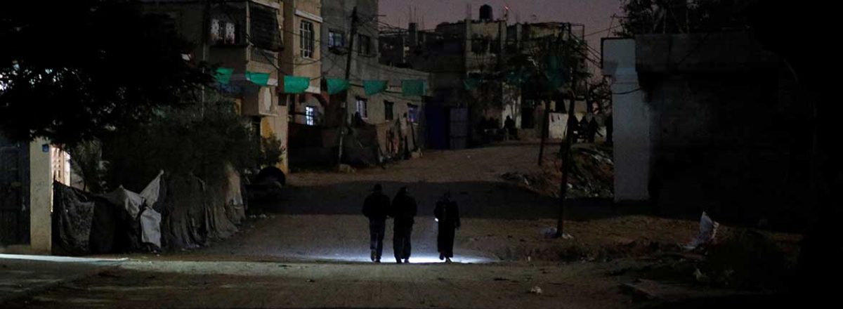 Palestinian women walk along unlit street in Gaza during power blackout. Photo by Mohammed Salem, Reuters, 11 Jan. 2017