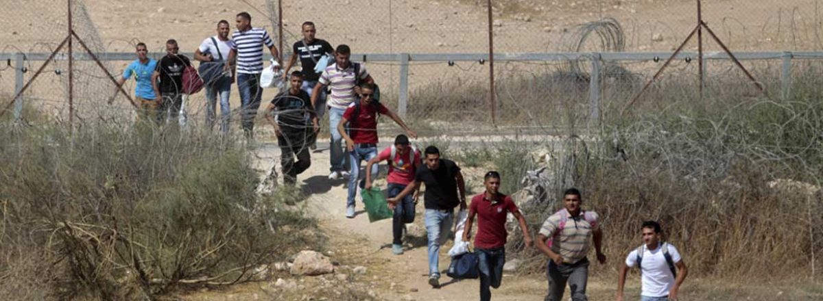 عمال فلسطينيون يركضون عبر فتحة في الجدار الفاصل جنوب الضفة الغربية. تصوير: عامر عواد، رويتريز. 6/7/2013.