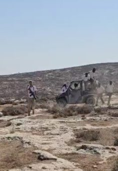 The armed settler alongside masked settlers. Photo courtesy of local residents