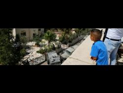 سكان في بيت سوريك يراقبون قوات الجيش التي وصلت الى بيت عائلة منفذ العملية في مستوطنة هار آدار. تصوير: عامر عواد، رويتيرز. 26.9.17.