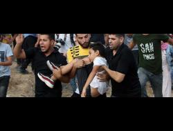 צעירים מפנים את עומר אבו א-ניל הפצוע לטיפול לאחר שנורה בצוורו בידי החיילים. צילום: עבד א-רחים ח'טיב
