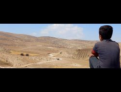 A boy watches military training in Masafer Yatta. Photo by Itai Itai Feitelson