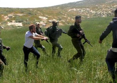 תמונה מתוך סרטון שצילם מתנדב בצלם, באסל אל-עדרה; מתנחל חמוש מלווה בידי חיילים מאיים על חקלאים פלסטינים בסמוך לא-תוואני, דרום הר חברון, 18.4.20