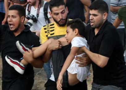 شبان يحملون المصاب عمر أبو النيل وينقلونه لتلقي العلاج بعدما أطلق الجنود الرصاص عليه وأصابوه في رقبته. تصوير: عبد الرحيم الخطيب