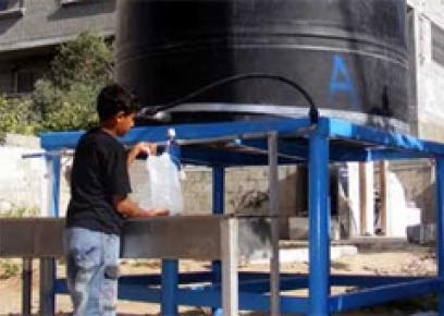 Child filling water from a container provided by OXFAM, at Jabalya refugee camp. Photo: Muhammad Sabah, B'Tselem, 18 Aug. '10.