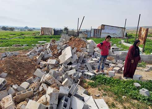 Family members of the homeowner standing by its ruins. Photo by ‘Aref Daraghmeh, B’Tselem, 22 Mar. 2022