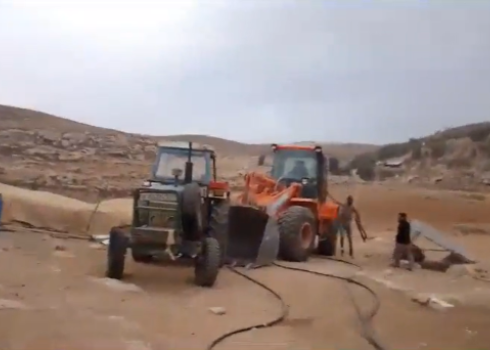 Settlers arrive at the community, one bearing a gun. Still from footage by a community resident 
