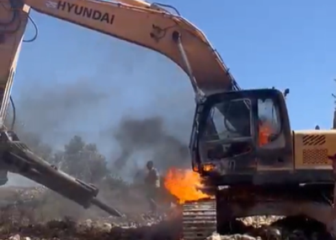 The excavator in flames after being torched by the settlers. Photo courtesy of local residents