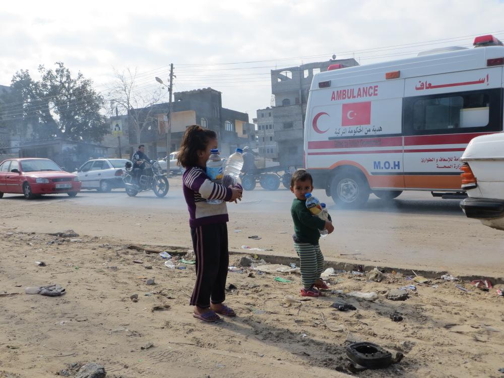 Children hauling water bottles near Khan Yunis Water Authority’s wastewater treatment plan. Photo by Muhammad Sabah, B’Tselem, 4 February 2014