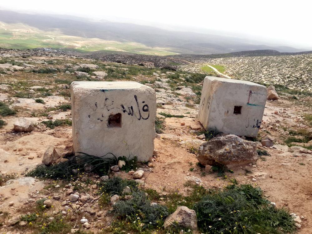 Concrete blocks placed by the military on the western access road to the Masafer Yatta area. The houses of Khirbet Jenbah are seen at the bottom of the valley.