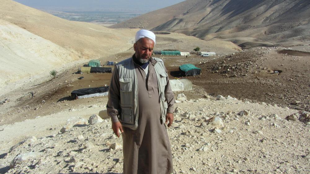 'Atiya Fathi Kassem Bani Minieh, resident of Karzaliyah against the background of the buildings of the community, as documented by Atef Abu A-Rub two weeks before the demolition, 23.12.13.