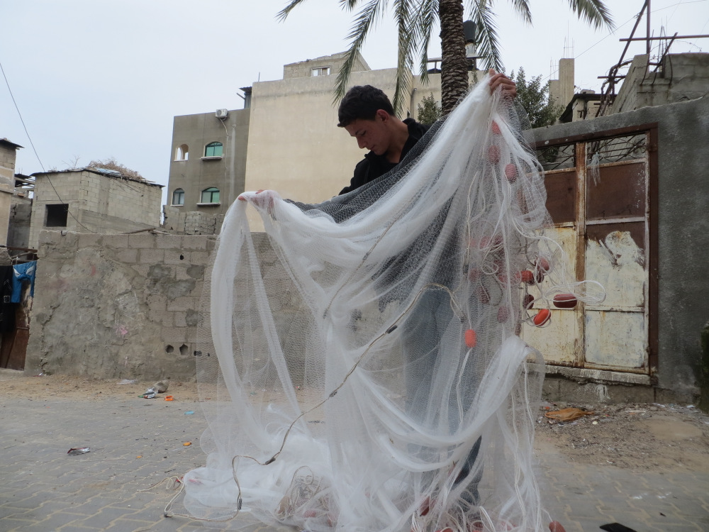 Fisherman Yusuf Abu Warda, 19, of Jabaliya, examines fishing net, 27 January 2014.