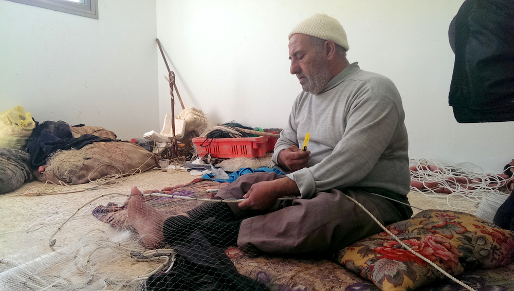 Fisherman Huseein al-'Amudi, 62, of a-Shati R.C., repairs fishing nets, 21 January 2014.