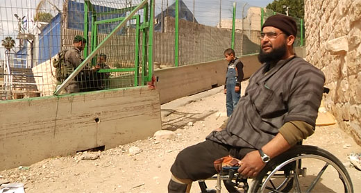 Burqan waiting while a Border Policeman opens the gate in the fence. Photo: Ramzi Maqdisi.
