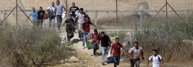  עובדים פלסטינים עוברים בריצה דרך פרצה במכשול ההפרדה בדרום הגדה המערבית. צילום: עמאר עוואד, רויטרס, 6.7.13. 