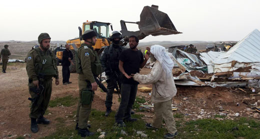 Residents of Um al-Kheir in the South Hebron Hills, against the backdrop of a bulldozer destroying structures in the community. Photo: Nasser Nawaj'ah, B’Tselem, 6 April 2016. תושבי אום אל-ח'ייר שבדרום הרב חברון וחיילים על רקע דחפור של המנהל האזרחי ההורס מבנה בקהילה. צילום: נסר נוואג'עה, בצלם, 6.4.16Residents of Um al-Kheir in the South Hebron Hills, against the backdrop of a bulldozer destroying structures in the community. Photo: Nasser Nawaj'ah, B’Tselem, 6 April 2016.