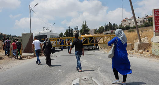 أشخاص يعبرون سيرًا على الأقدام عند بوابة في بيت عينون من أجل الوصول إلى سيارات الأجرة في الجانب الثاني. تصوير: نصر نواجعة، بتسيلم، 4/7/2016.