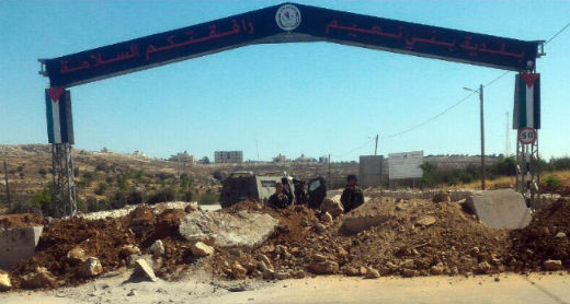 جنود يحرسون على ساتر ترابيّ نصب الجيش عند مدخل بلدة بني نعيم الرئيسيّ. تصوير: نصر نواجعة، بتسيلم، 30/6/2016.