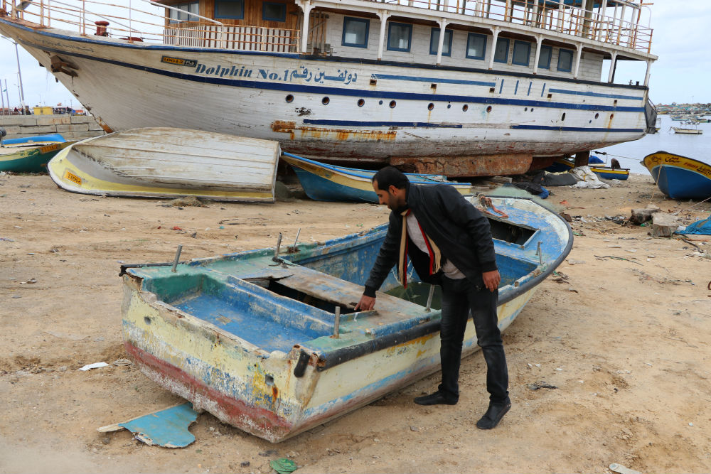 אחמד אבו חמאדה ליד הסירה המושבתת שלו. צילום: מוחמד סבאח, בצלם, 26.1.17